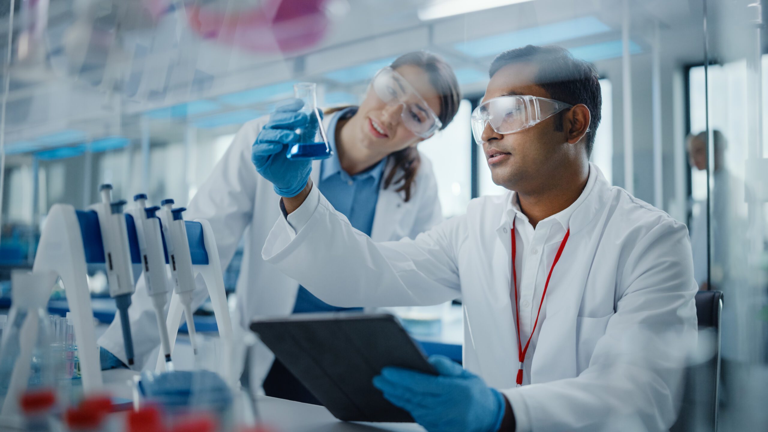 Scientists in a modern lab looking at blue liquid in a beaker