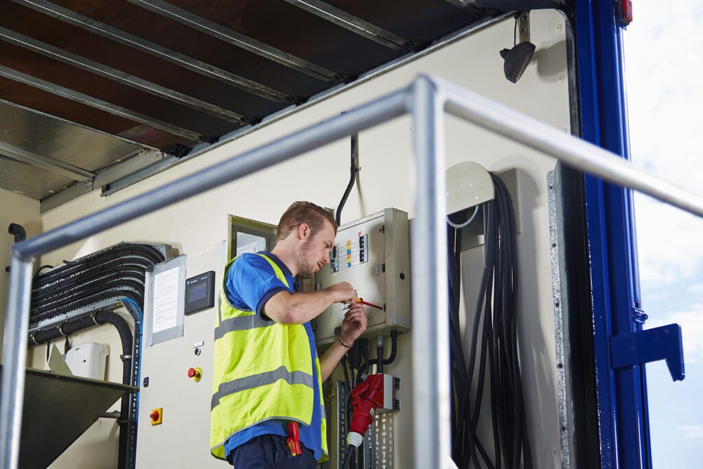 Technician working on electric box inside a container unit 